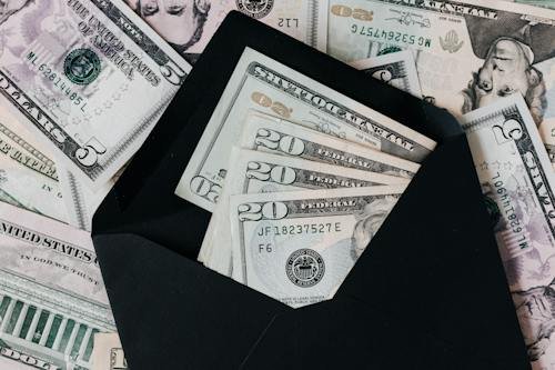 Free From above of dollar bills in opened black envelope placed on stack of United states cash money as concept of personal income Stock Photo